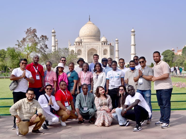 Large group of tourists posing together in front of the Taj Mahal on a sunny day